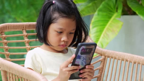 アジアの女の子は スマートフォンを見て 常に注意深く見て 眉をひそめて 目を使って スマートフォンのタブレットを長い間見て 病気を引き起こす可能性があるAdhdの問題 — ストック動画