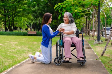 Tekerlekli sandalyedeki hastayla ilgilenen Asyalı dikkatli bir bakıcı ya da hemşire. Bakıcının, birikimin ve sağlık sigortasının özenle mutlu emeklilik kavramı. Mutlu bir aile.