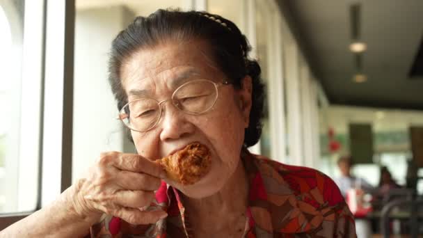 有选择地关注炸鸡 亚洲老年妇女正在吃炸鸡 在餐馆里 老龄化社会的概念 退休后的准备 幸福生活 — 图库视频影像