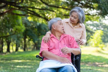 Parkta kıdemli bir çift ve karısı tekerlekli sandalyedeki bir kocaya bakıyorlar felçli bir hasta, karısı birbirlerini teselli ediyor ve cesaretlendiriyor. Emeklilik sağlık sigortası kavramı.