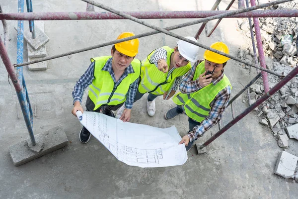 Top view of Asian engineer or Young Female Architect put on a helmet for safety and talk with a contractor on a construction building factory project, Concept of Teamwork, Leadership concept.
