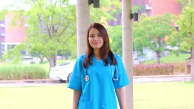 Mavi önlük giyen, kendine güvenen, mutlu ve gülümseyen Asyalı doktor ya da hemşire portresi..