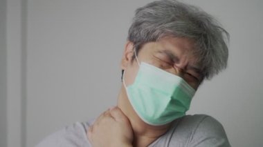 Tıbbi maske takan hasta Asyalı bir adam ve baş ağrısını tutmak için elini uzat. Korunma pandemik koronavirüs ve solunum hastalığı kavramı