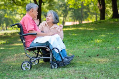 Parkta kıdemli bir çift ve karısı tekerlekli sandalyedeki bir kocaya bakıyorlar felçli bir hasta, karısı birbirlerini teselli ediyor ve cesaretlendiriyor. Emeklilik sağlık sigortası kavramı.