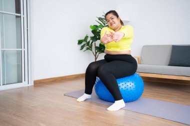 Portre ve beden ölçülerinde bir kadın spor salonunda spor yapıyor. Şişman bir kadın pilates topunda oturup egzersiz yapmadan önce kaslarını esnetiyor. Sağlık ve kilo kaybı kavramı.