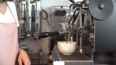 Restoranda ya da kahve dükkanında kahve makinesiyle taze espresso yapan profesyonel bayan baristanın yakın çekimi. Barista Hazırlık veya Girişimci Kahve Makinesi konsepti kendi dükkanında