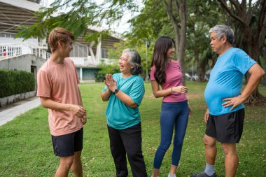 Healthy family group instructors workout in fresh air, and they rest and stand together after morning exercises in park. Outdoor activities, healthy lifestyle, strong bodies, fit figures, health care.
