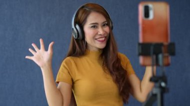 Mutlu genç Asyalı kadınlar güzel blogcular sosyal medya uygulamaları için kulaklık ve video kayıt kullanıyorlar. Özgürlük ve aktif yaşam tarzı konsepti, canlı video üzerinden satışları iletin.