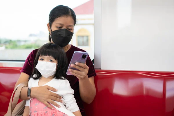 Little girl and mom with surgical mask face protection flu and Virus outbreak in public transportation. Concept of New normal lifestyle, Using public transport to travel to school