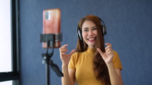 快乐的年轻亚洲女性美丽博客使用耳机 并在智能手机上录制视频 用于社交媒体应用 自由和积极的生活方式概念 通过现场直播销售 — 图库视频影像