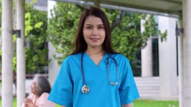 Mavi önlük giyen, kendine güvenen, mutlu ve gülümseyen Asyalı doktor ya da hemşire portresi..