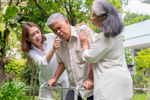 Happy old elderly Asian man uses a walker and walks in the backyard with him Nurse and wife.  Concept of happy retirement With care from a caregiver and Savings and senior health insurance