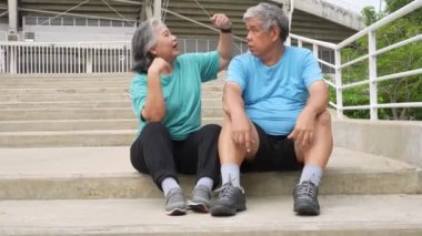 Happy and smile couples elderly asian sitting on stairs for rest after workout, jogging on morning, senior exercise outdoor for good healthy. Concept of healthcare and active lifestyle for healthy