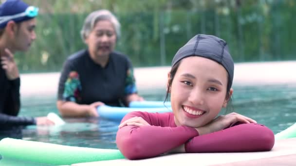 先輩女性のエアロビクスの前でアクアの中の若いトレーナーの女性の肖像とプールで働きます スイミングプールでアクアエアロビクスの練習を行う老婦人 高齢者スポーツ — ストック動画