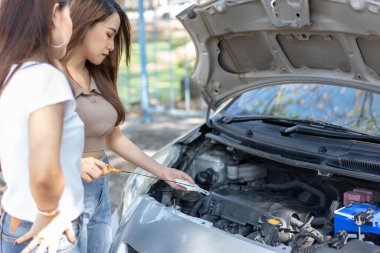 İki Asyalı araba motorunu kontrol etmeye ve yolda bir araba arızasından sonra yardım beklemeye çalışıyor. Araç motoru sorunu veya kaza kavramı ve profesyonel bir tamirciden acil yardım