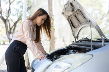Kızgın Asyalı kadın, caddedeki bir araba arızasından sonra akıllı telefondan VIDEO konferansını yardım için kullanıyor. Araç motoru sorunu veya kaza kavramı ve profesyonel bir tamirciden acil yardım