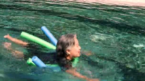若いトレーナーは アクアエアロビクスのシニア女性を助け プールで働いています スイミングプール 高齢者スポーツ アクティブなライフスタイルの概念でアクアエアロビクスの練習を行う老婦人と成熟した男 — ストック動画