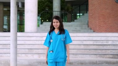 Mavi önlük giyen, kendine güvenen, mutlu ve gülümseyen Asyalı doktor ya da hemşire portresi..
