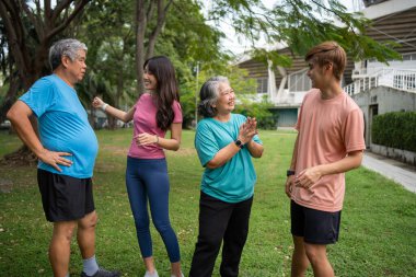 Healthy family group instructors workout in fresh air, and they rest and stand together after morning exercises in park. Outdoor activities, healthy lifestyle, strong bodies, fit figures, health care.