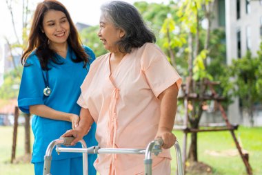 Asian careful caregiver or nurse hold patient hand and encourage patient, walking in garden. Concept of happy retirement with care from a caregiver and Savings and senior health insurance.