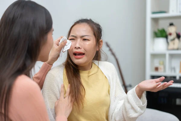 stock image Two women talking about problems at home. Asian women embrace to calm their sad best friends from feeling down. Female friends supporting each other. Problems, friendship, and care concept