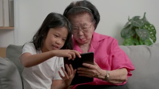 소파에 태블릿을 사용하여 할머니와 손녀가 있었다 할머니와 손자가 비디오 태블릿을 — 비디오