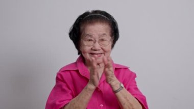 Mutlu yaşlı büyükannem mutlu ve gülümsüyor ve el çırpıyor. Şanslı yaşlı kadın alkışlıyor. Beyaz arka planda izole edilmiş eğleniyor.