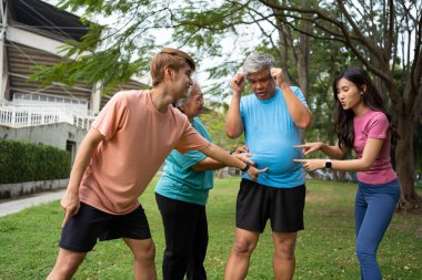 Healthy family group instructors workout in fresh air, and they rest and stand together after morning exercises in park. Outdoor activities, healthy lifestyle, strong bodies, fit figures, health care.