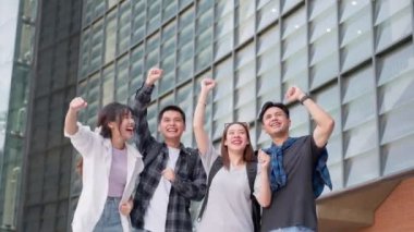 Bir grup mutlu genç girişimci ellerini kaldırmış ve kutlamak için gülüyorlar ve elde ettikleri başarılar için heyecanlılar. Lisans öğrencileri, başarı üstüne başarı ve takım çalışması kavramını kutladılar