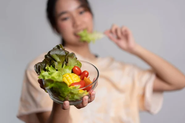 家庭でのワークアウトの後 ガラスのボウルから新鮮なサラダを食べる幸せな遊び心のあるアジアの女の子の肖像画 若い女性は健康的な栄養と有機食品を楽しんでいます ベジタリアン食事を持ちます — ストック写真
