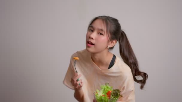描述了一个快乐 嬉闹的亚洲女孩在家里锻炼后从玻璃碗里吃新鲜沙拉的形象 享受健康营养和有机食品 有素食的年轻女士 — 图库视频影像