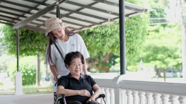 Азиатский Заботливый Ухаживающий Внучка Счастливый Пациент Инвалидной Коляске Прогуливаются Саду — стоковое видео