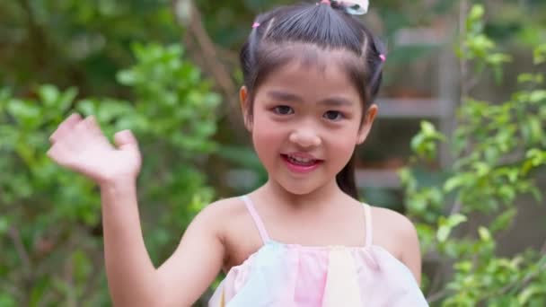 Çekici Bir Asyalı Kızın Portresi Gülümseyip Kameraya Bakıyor Elini Sallıyor — Stok video