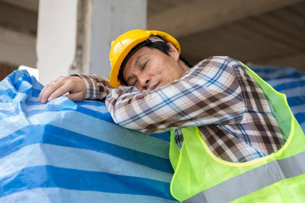 Construction worker with white safety helmet take a nap because so are tired from working in the hot sun on construction site, Sleeping during work, sleep at workplace, Over time employee. Copy Space