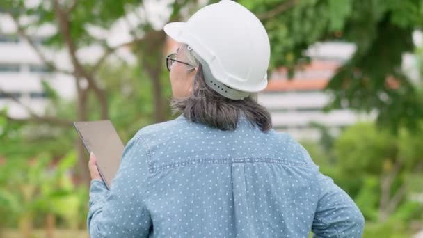 积极年龄亚洲女性建筑在硬帽架 石碑和立于城前的建筑施工完工后检查建筑 施工理念 — 图库视频影像