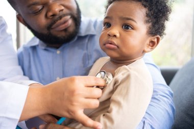 Ciğerleri stetoskoplu pediatri doktoru ya da tıbbi sağlık hastanesinde ya da klinikte küçük şirin bir kızı muayene etmek için göğüs muayenesi. Doktor, gülümseyen Afrikalı Amerikalı Bebek İçin Kalp ve Akciğerleri kontrol et.