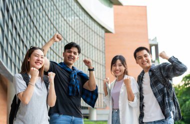 Bir grup mutlu genç girişimci ellerini kaldırmış ve kutlamak için gülüyorlar ve elde ettikleri başarılar için heyecanlılar. Lisans öğrencileri, başarı üstüne başarı ve takım çalışması kavramını kutladılar