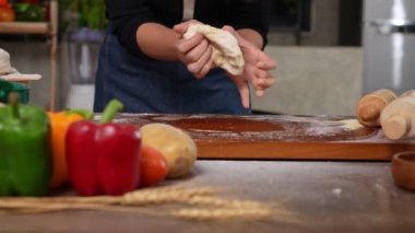 Mutfakta durup pizza hamuru yoğuran önlük giymiş neşeli bir kadın. Fırında elle para kazanıyordum. Evde pizza için hamur hazırlamak, pizza ekmeği hazırlamak ya da pasta hazırlamak.
