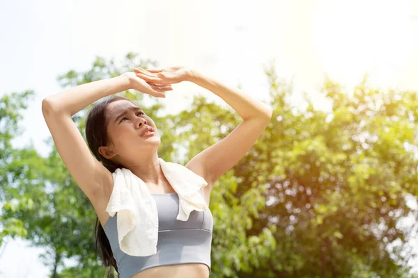 Sport asian woman gets tired and get dizzy, feel bad pain and suffer from heat stroke outdoors when jogging or exercise outdoor with strong sunlight in summer season. Heatstroke and heat wave concept.