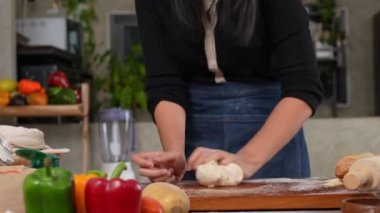 Mutfakta durup pizza hamuru yoğuran önlük giymiş neşeli bir kadın. Fırında elle para kazanıyordum. Evde pizza için hamur hazırlamak, pizza ekmeği hazırlamak ya da pasta hazırlamak.