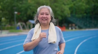 Üst düzey kadın stadyumda koşuyor. Yaşlı kadın kişi yaz aylarında yürürken ya da koşarken sağlık ve sağlık için kardiyo yapmaktan mutludur. Sağlıklı yaşam için sağlık ve aktif yaşam biçimi kavramı