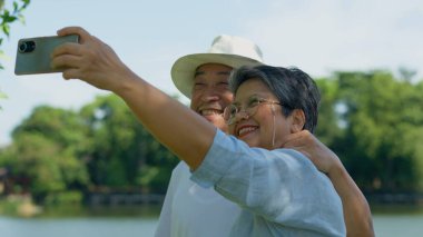 Mutlu ve sağlıklı çiftler Asyalı fotoğraf ve VLOG selfie 'si boş zamanlarında parkta sosyal medya için birlikte. Aile ve arkadaşlık yaşam tarzı, aktif yaşlıların keyfi ve emeklilikten sonra açık hava aktiviteleri.