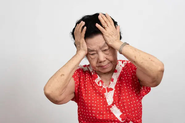 A senior woman who has a severe headache suffers from a stroke ,brain disease,patient holding head with her hand,suffering from senile dementia,memory disorders, confused old elderly with Alzheimer