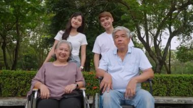 Bir grup mutlu büyükanne ve torun birlikte konuşuyor ve gülüyor, büyükbaba tekerlekli sandalyede oturuyor. Aile ile emeklilik hayatı, aile içinde iyi bir nesil ilişkisi. son sınıf yaşam konsepti