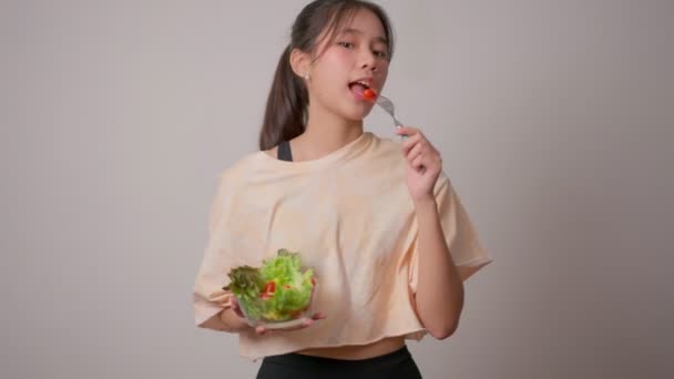 描述了一个快乐 嬉闹的亚洲女孩在家里锻炼后从玻璃碗里吃新鲜沙拉的形象 享受健康营养和有机食品 有素食的年轻女士 — 图库视频影像