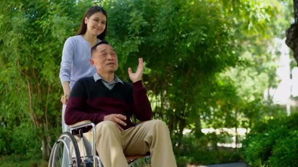 アジア人介護者や看護師が車椅子で患者の世話をする 介護者の介護による幸せな退職の概念と貯蓄と高齢者健康保険 幸せな家族 — ストック動画