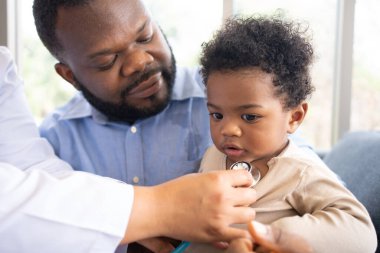 Ciğerleri stetoskoplu pediatri doktoru ya da tıbbi sağlık hastanesinde ya da klinikte küçük şirin bir kızı muayene etmek için göğüs muayenesi. Doktor, gülümseyen Afrikalı Amerikalı Bebek İçin Kalp ve Akciğerleri kontrol et.