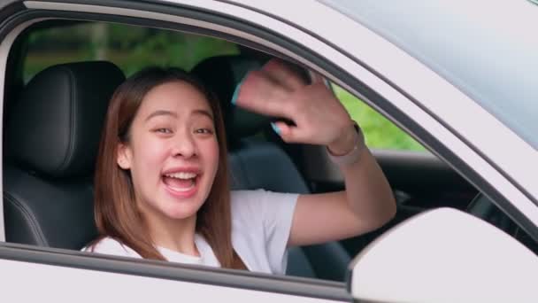 快乐的亚洲女人坐在车后掌舵和挥手 快乐司机的概念 汽车保险服务 顾客们买了新车后都很兴奋 新司机们也很兴奋能拿到汽车牌照 — 图库视频影像