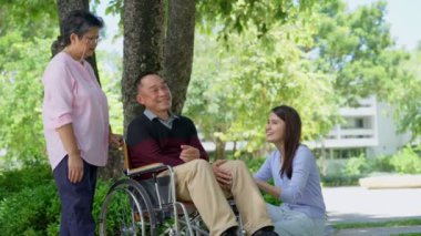 Tekerlekli sandalyedeki hastayla ilgilenen ve annesiyle konuşan bir kız. Bakıcının, birikimin, sağlık sigortasının, mutlu bir ailenin ve emekliliğin özenle mutlu emeklilik kavramı.