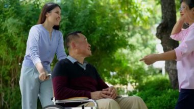 Tekerlekli sandalyedeki hastayla ilgilenen ve annesiyle konuşan bir kız. Bakıcının, birikimin, sağlık sigortasının, mutlu bir ailenin ve emekliliğin özenle mutlu emeklilik kavramı.